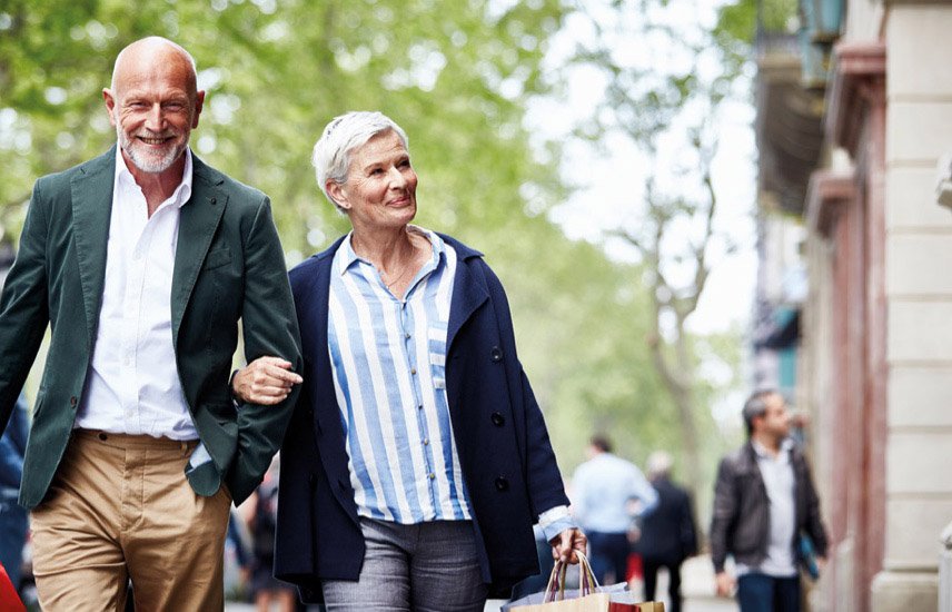 Senior man and woman, arm in arm, walking along street looking at shops - close to the Pavilions Blackburn Lake